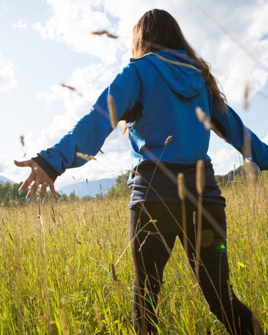 woman in field with arms stretched